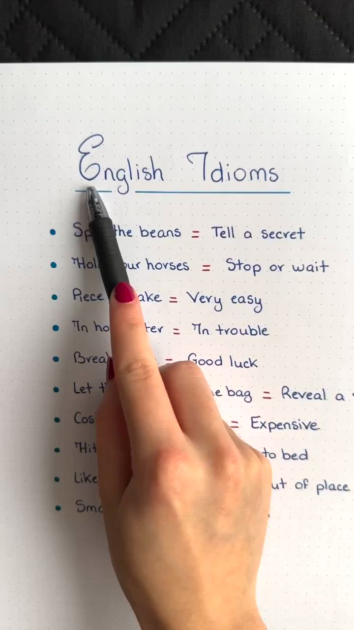 This may contain: a person writing english idioms on a piece of paper with a pen in their hand