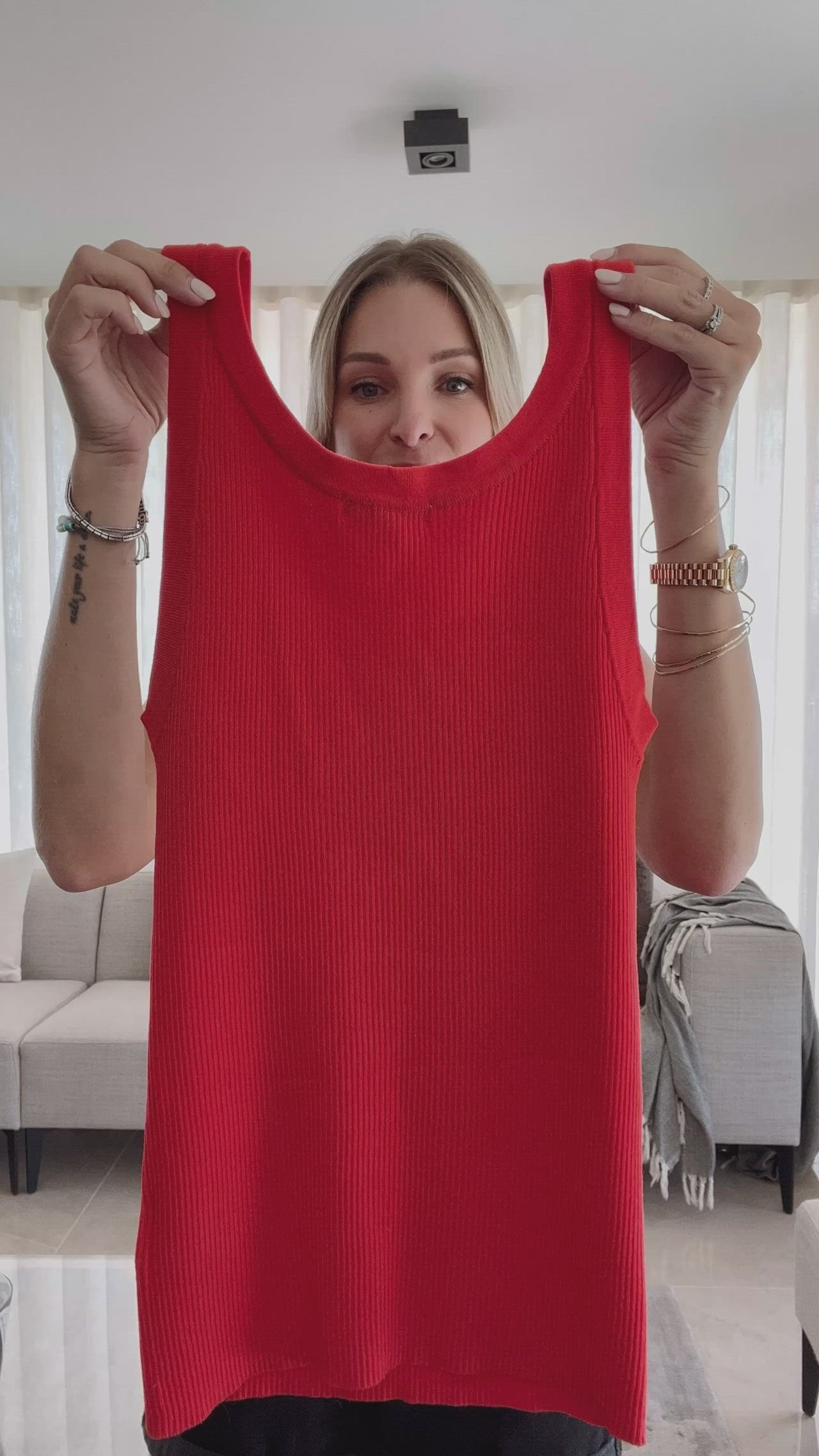 This may contain: a woman holding up a red tank top in front of her face