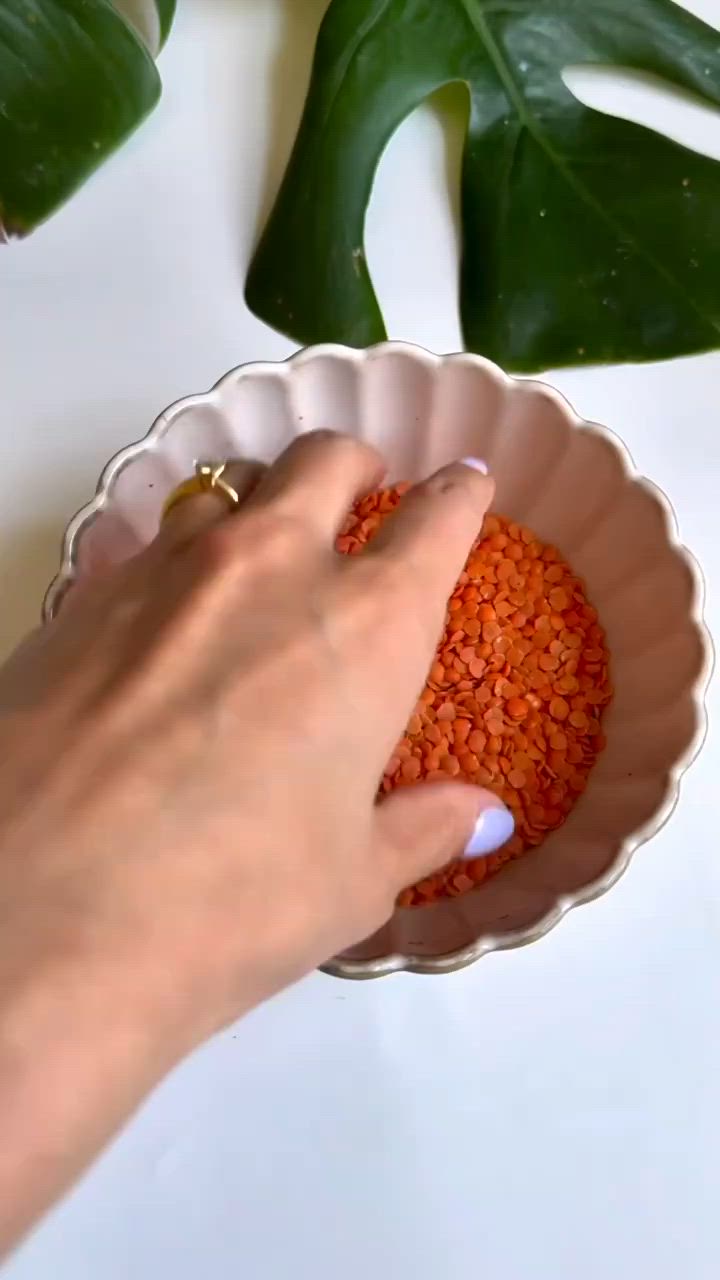 This may contain: a woman's hand holding a red object in a white bowl on top of a table