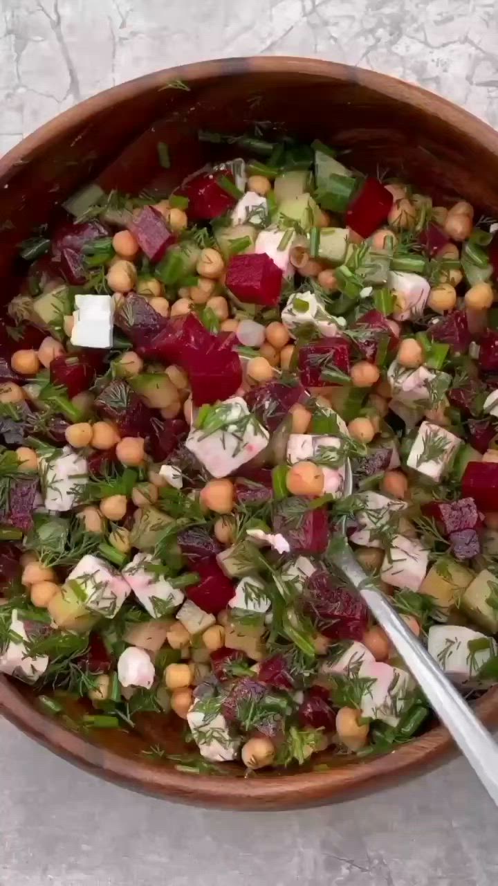 This may contain: a wooden bowl filled with lots of different types of vegetables and garnishes