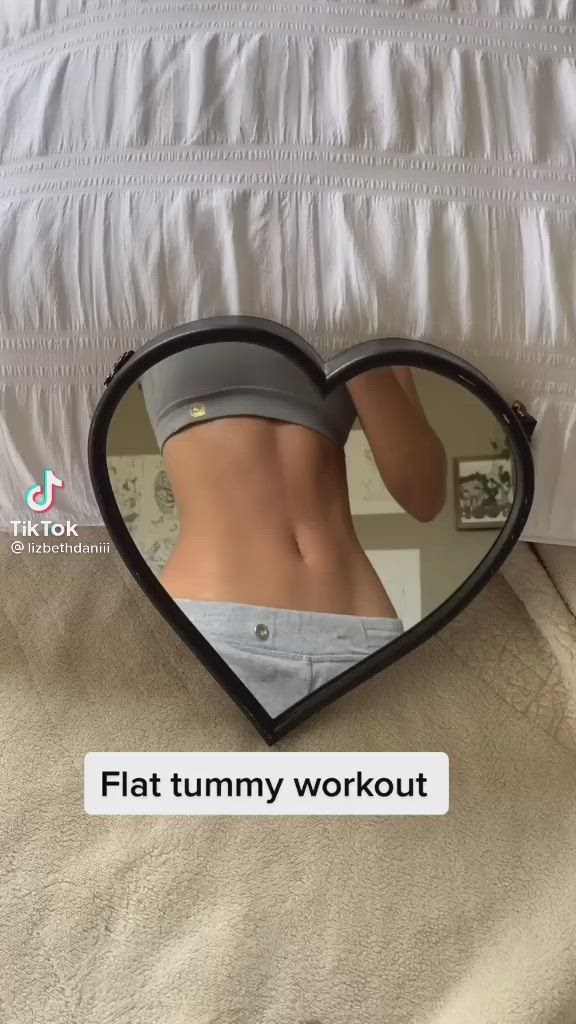 This may contain: a heart shaped mirror with a woman's stomach in the middle and text that reads, flat tummy workout