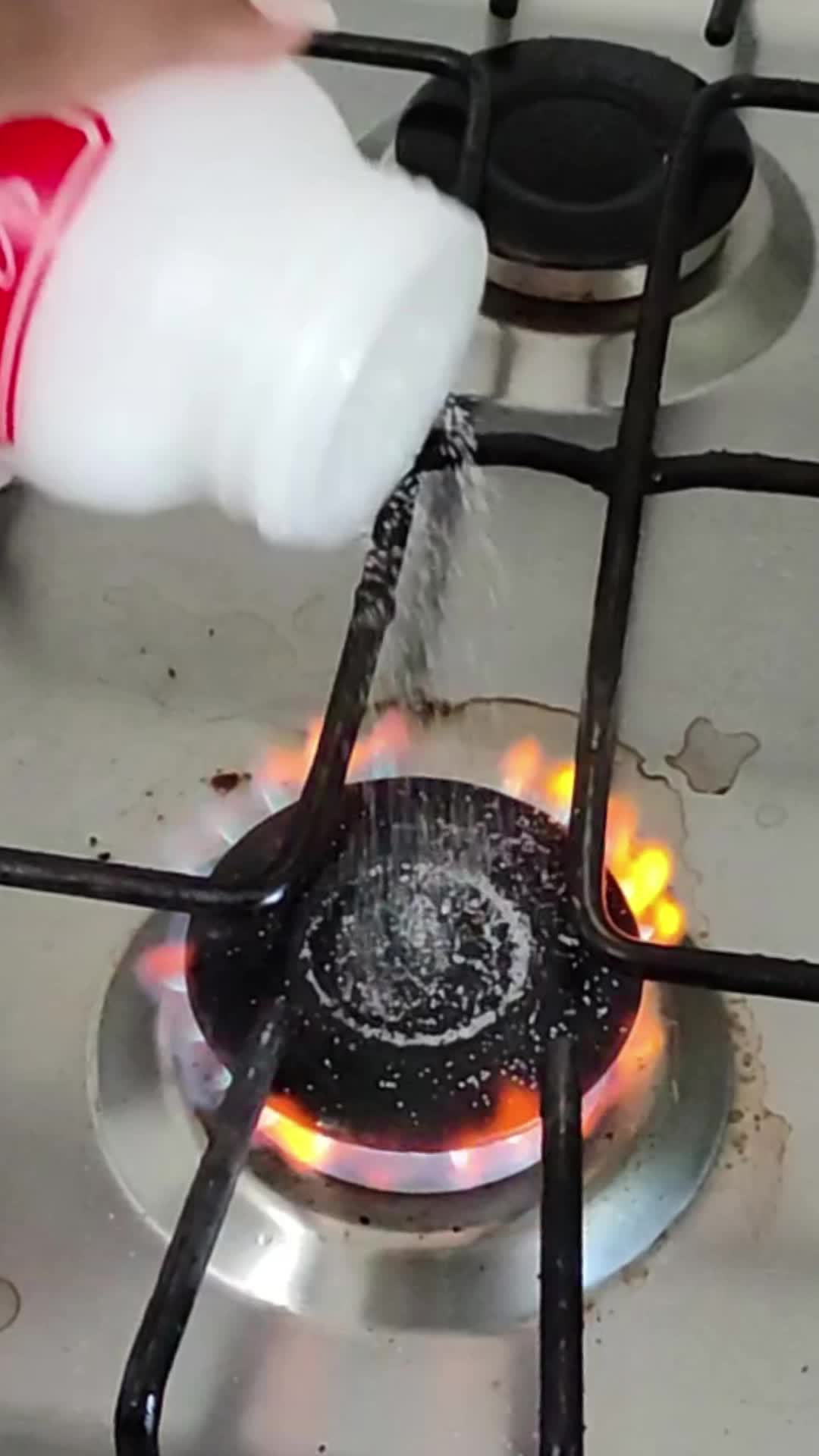 This may contain: a person is cooking on a stove with flames coming out of it and holding a white glove over the burner