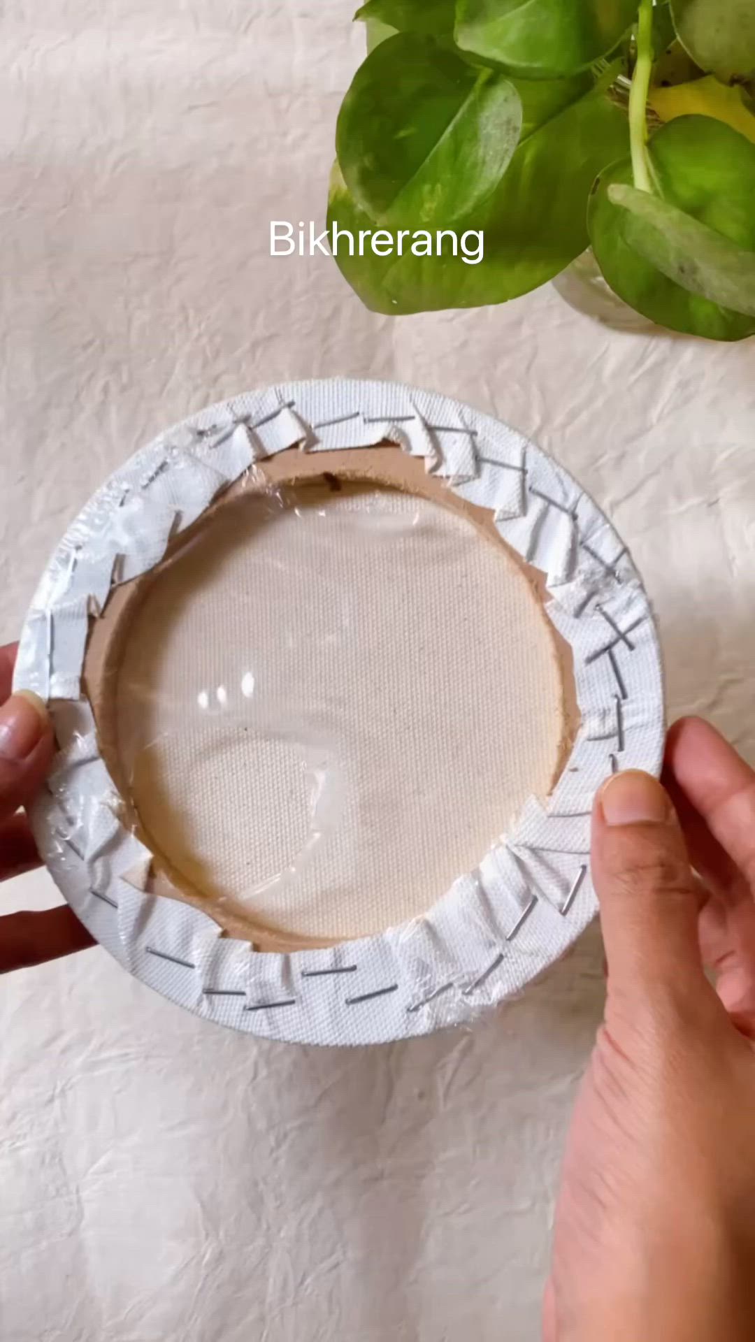 This may contain: a blue and white crocheted evil eye coaster on a wooden stand with a plant in the background