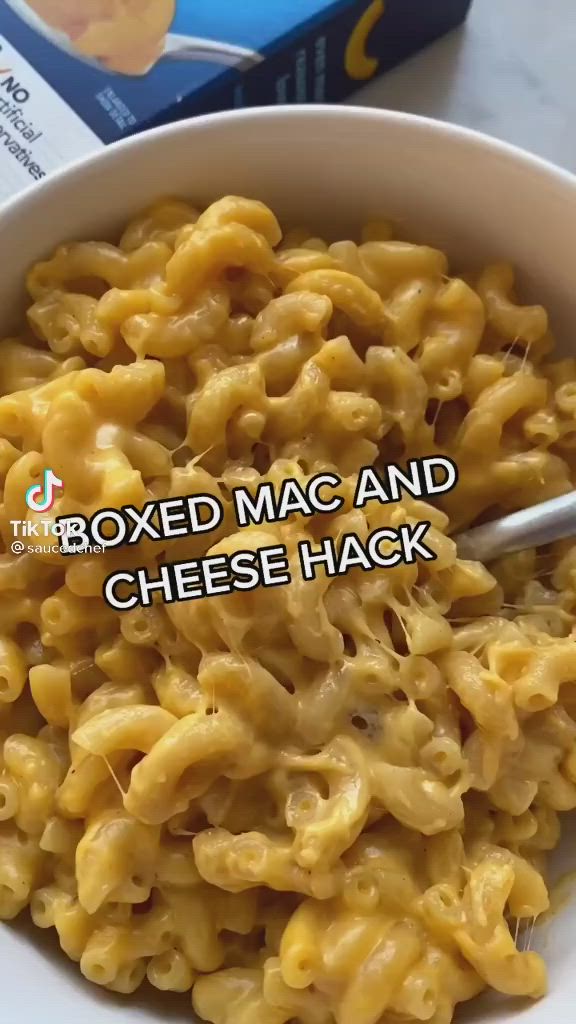 This may contain: a white bowl filled with macaroni and cheese next to a box of macaroni and cheese