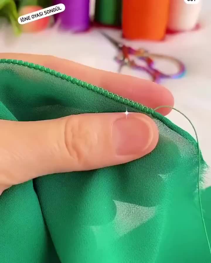 This may contain: someone is stitching the thread on their green fabric with scissors and other sewing supplies in the background