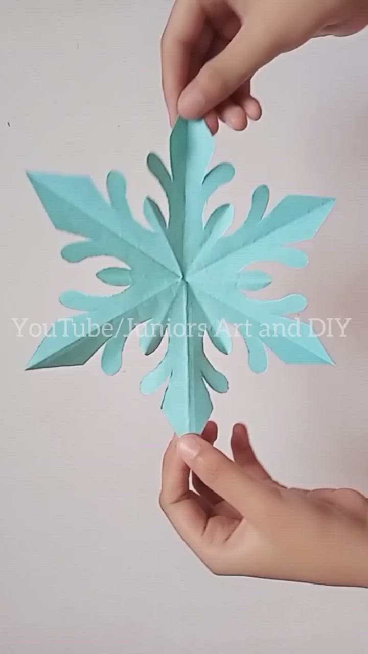 This may contain: two hands holding an origami snowflake with one hand and another hand reaching for it