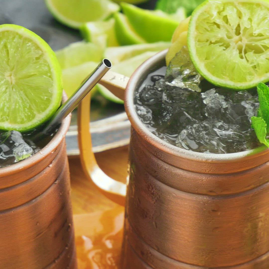 This may contain: two copper mugs filled with limeade and mint garnish