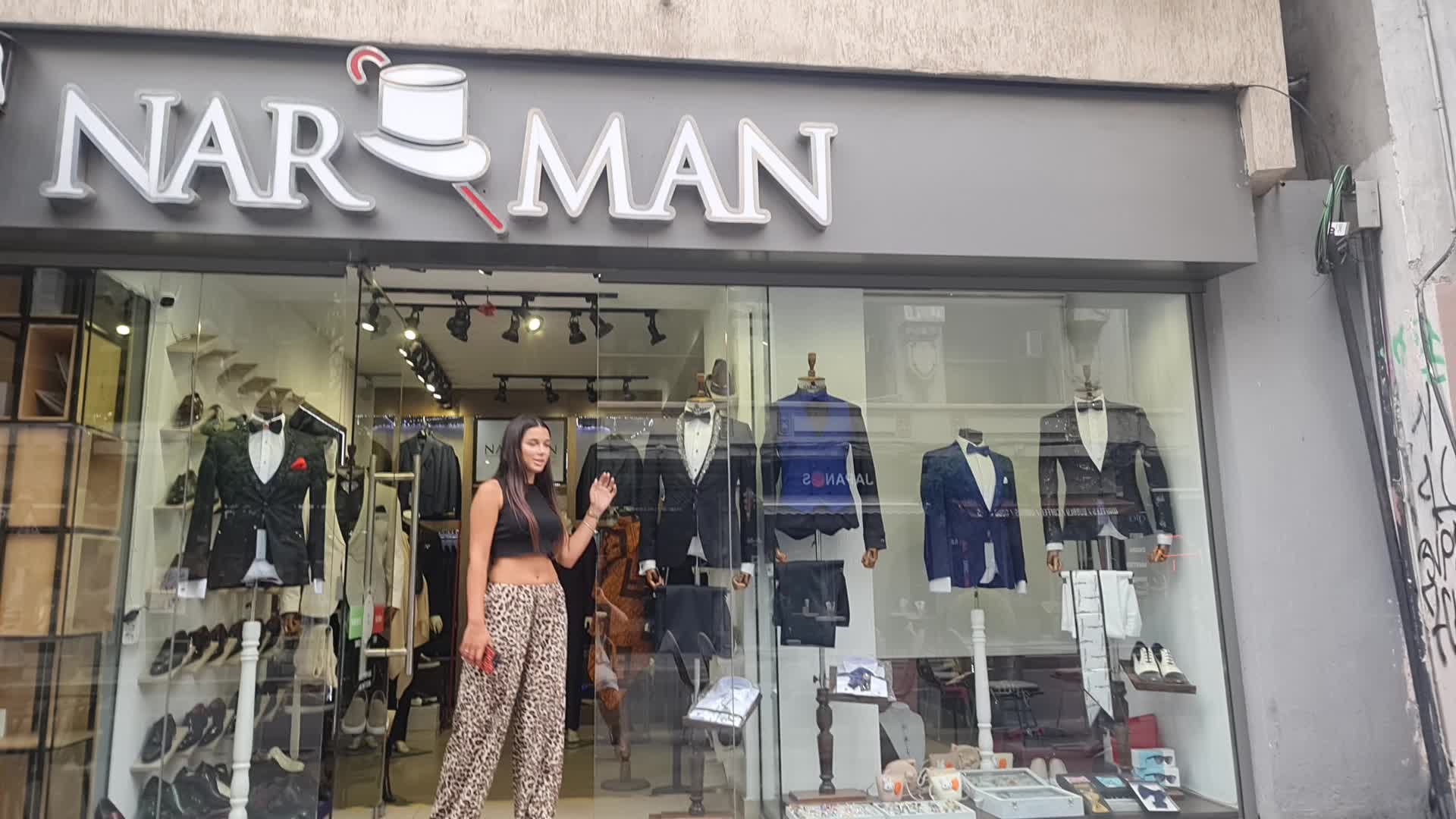 This may contain: a woman standing in front of a clothing store