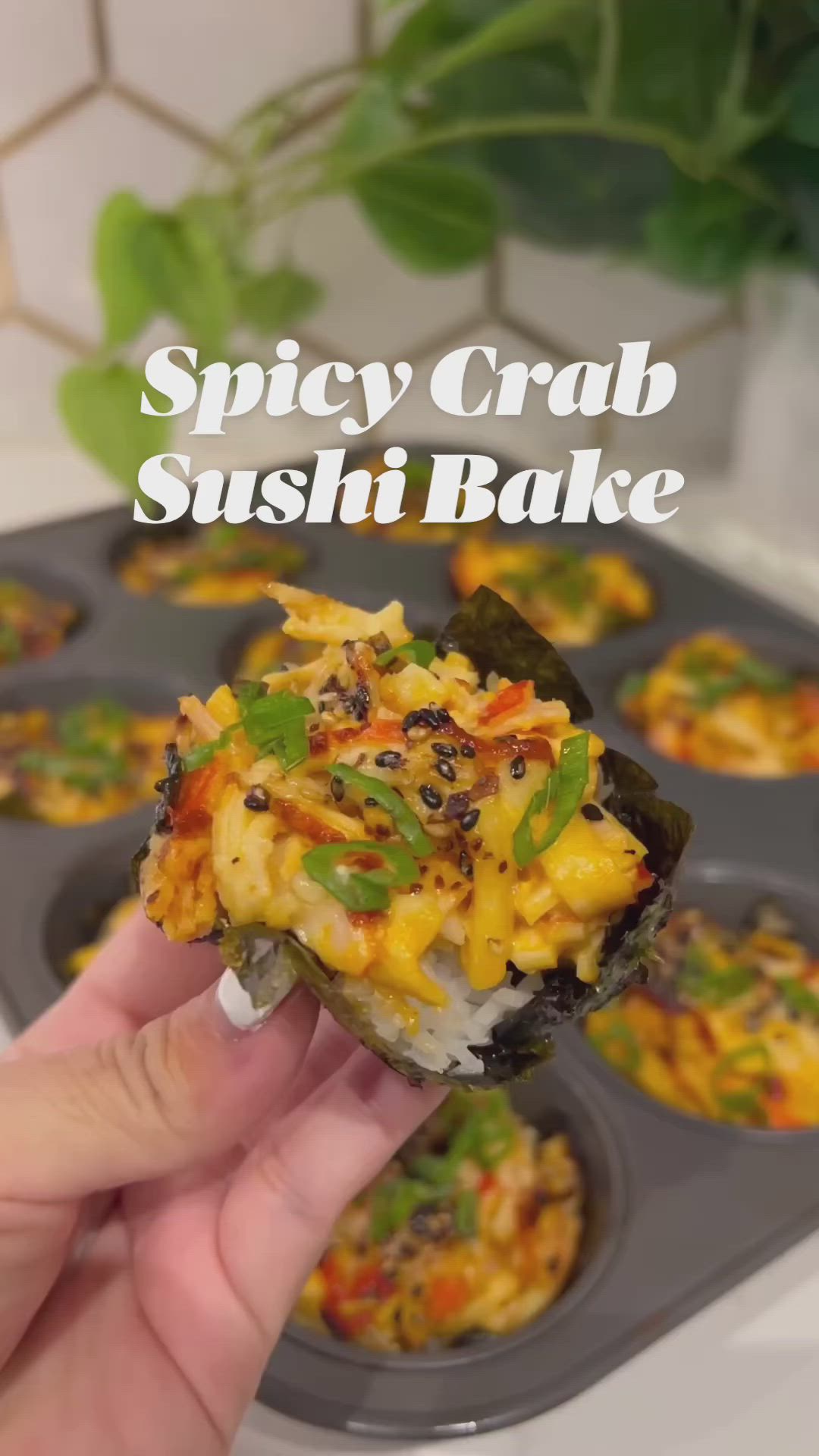 This may contain: someone is holding up some food in a muffin tin with the words spicy crab sushi bake on it