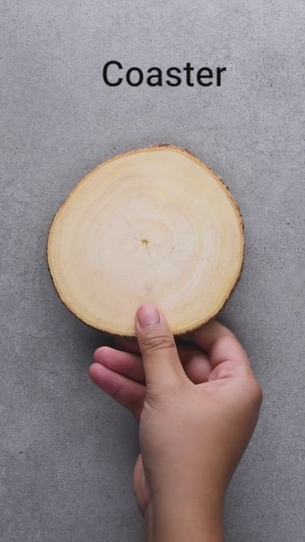 This may contain: a person holding a piece of wood with the word coaster in front of them on it