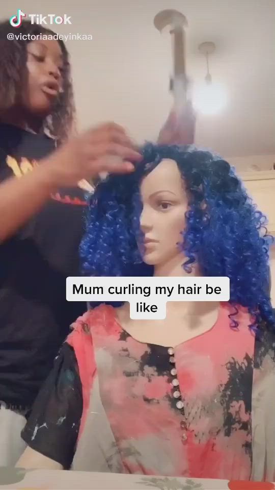 This may contain: a woman with blue hair is cutting another woman's hair in front of the camera