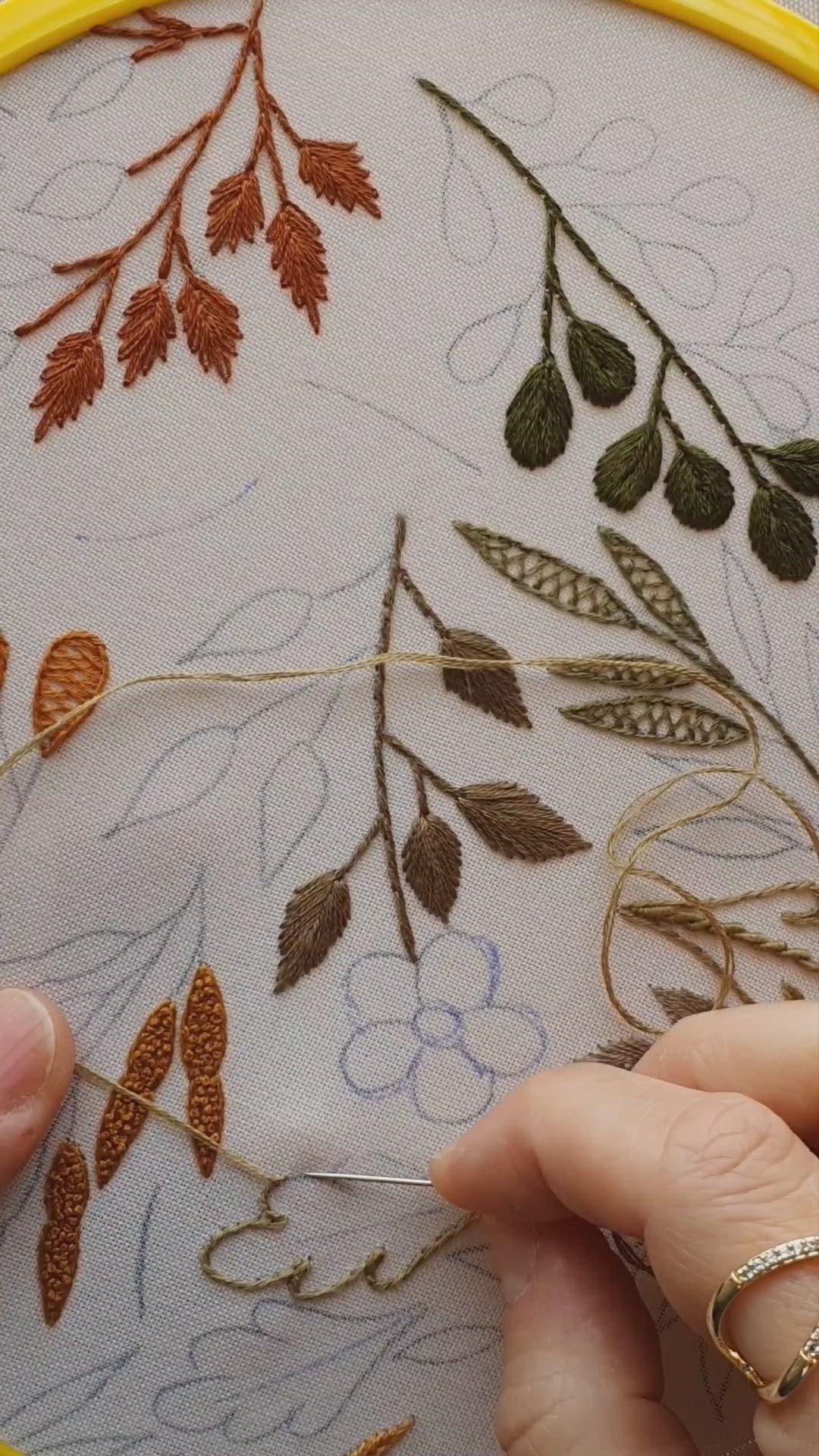 This may contain: a close up of a embroidery on a white piece of cloth with flowers and leaves