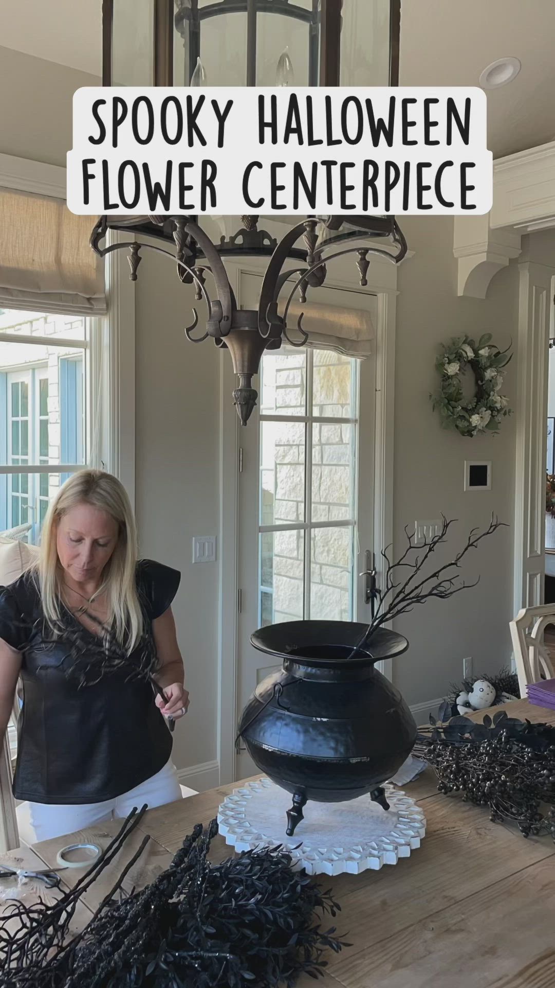 This may contain: a woman standing in front of a black pot with flowers on it and the words spooky halloween flower centerpiece