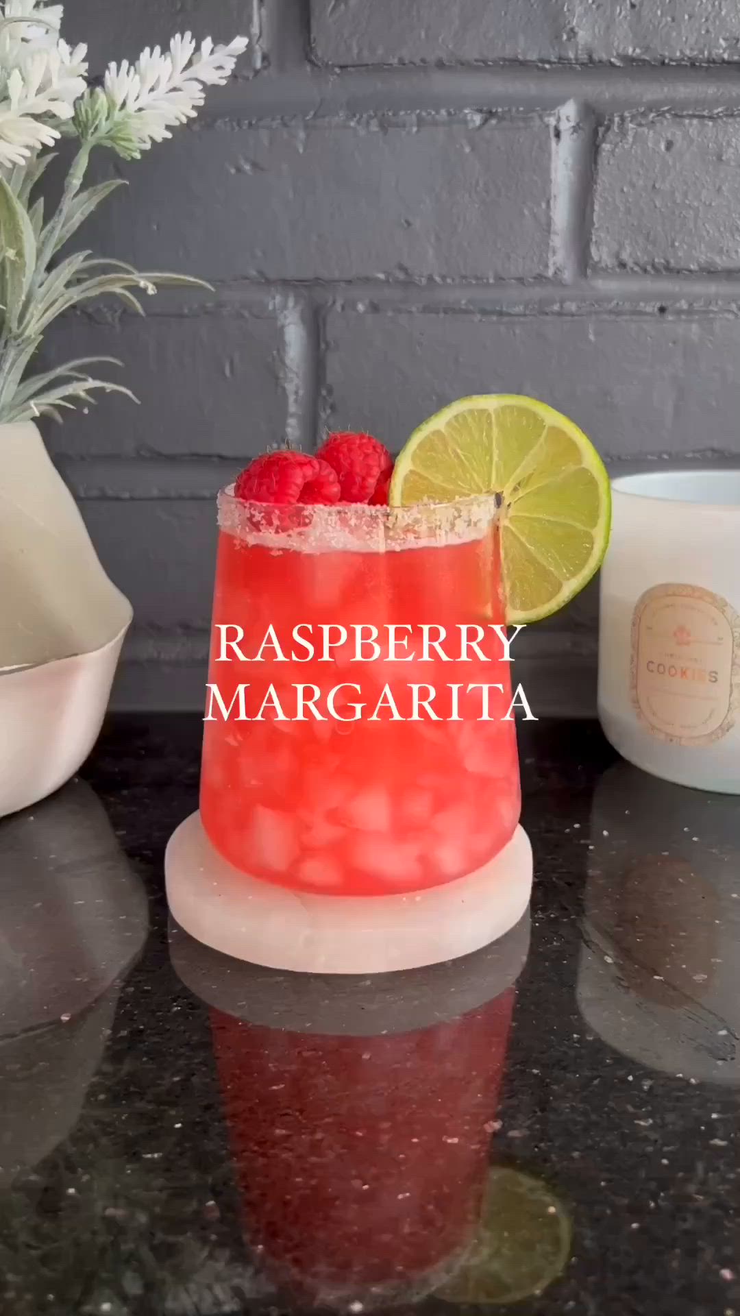 This may contain: raspberry margarita with lime and strawberries in a glass on a counter top