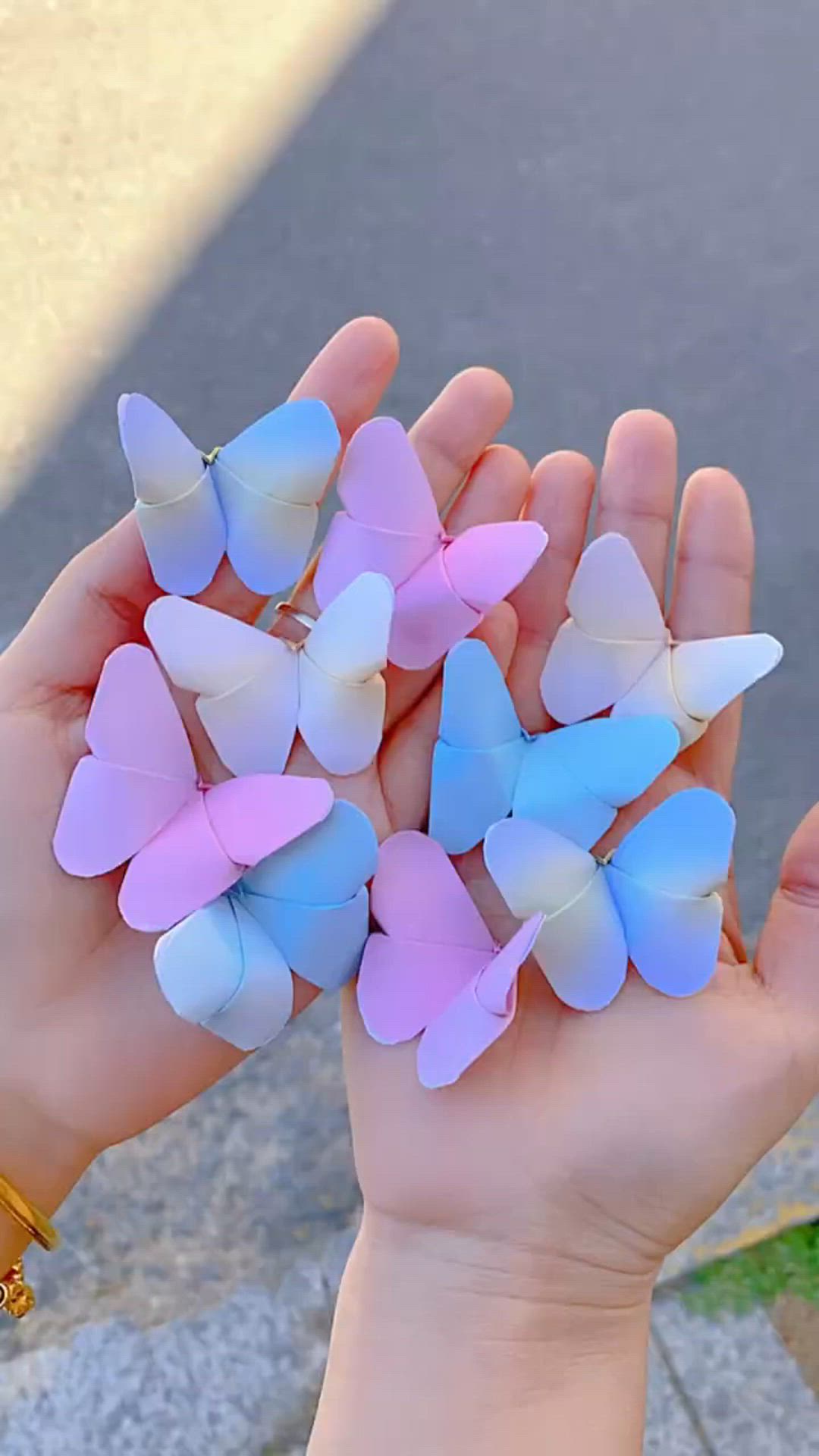 This may contain: a person holding several small butterflies in their hands with glitters on the ground behind them