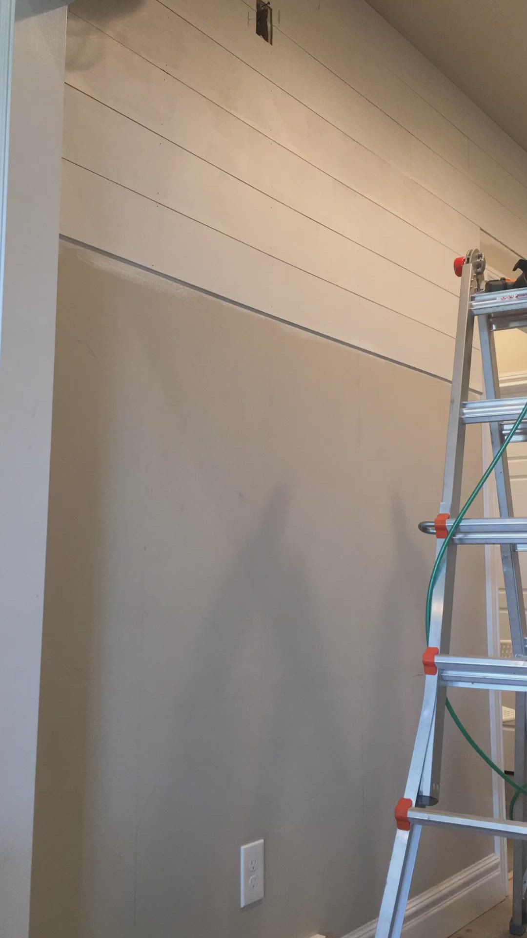 This may contain: two people on a ladder painting the walls in a room that is being painted white