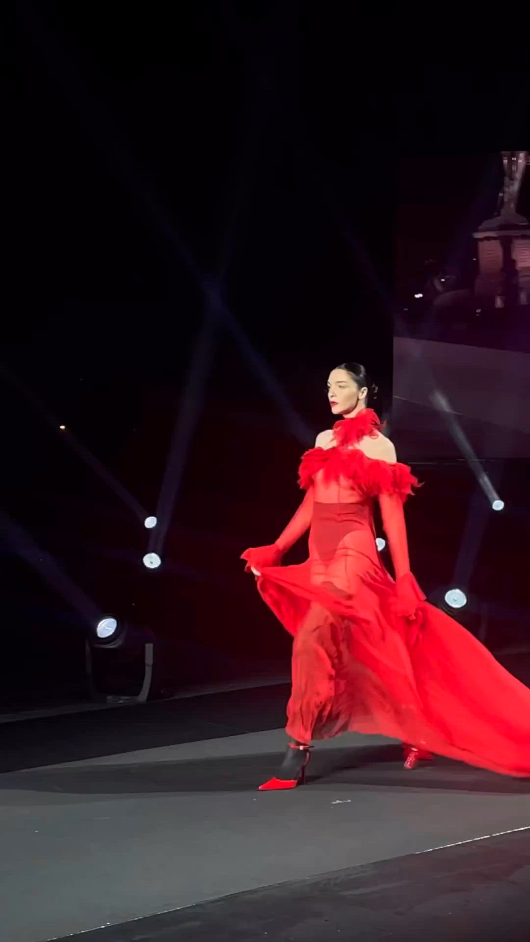 This may contain: a woman in a red dress is walking down the runway