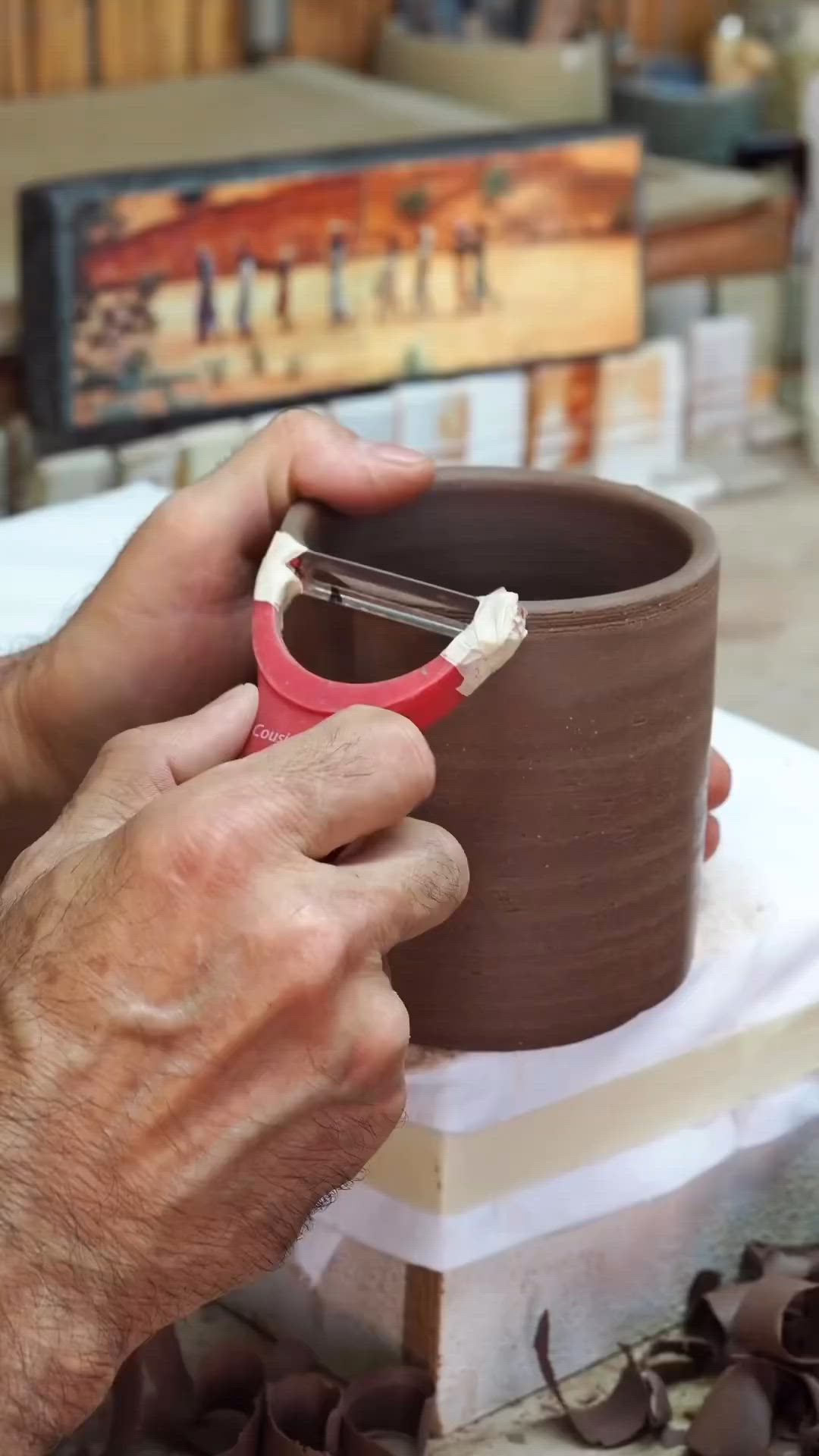 This may contain: a person is holding a cup in their hand while working on some clay and other items