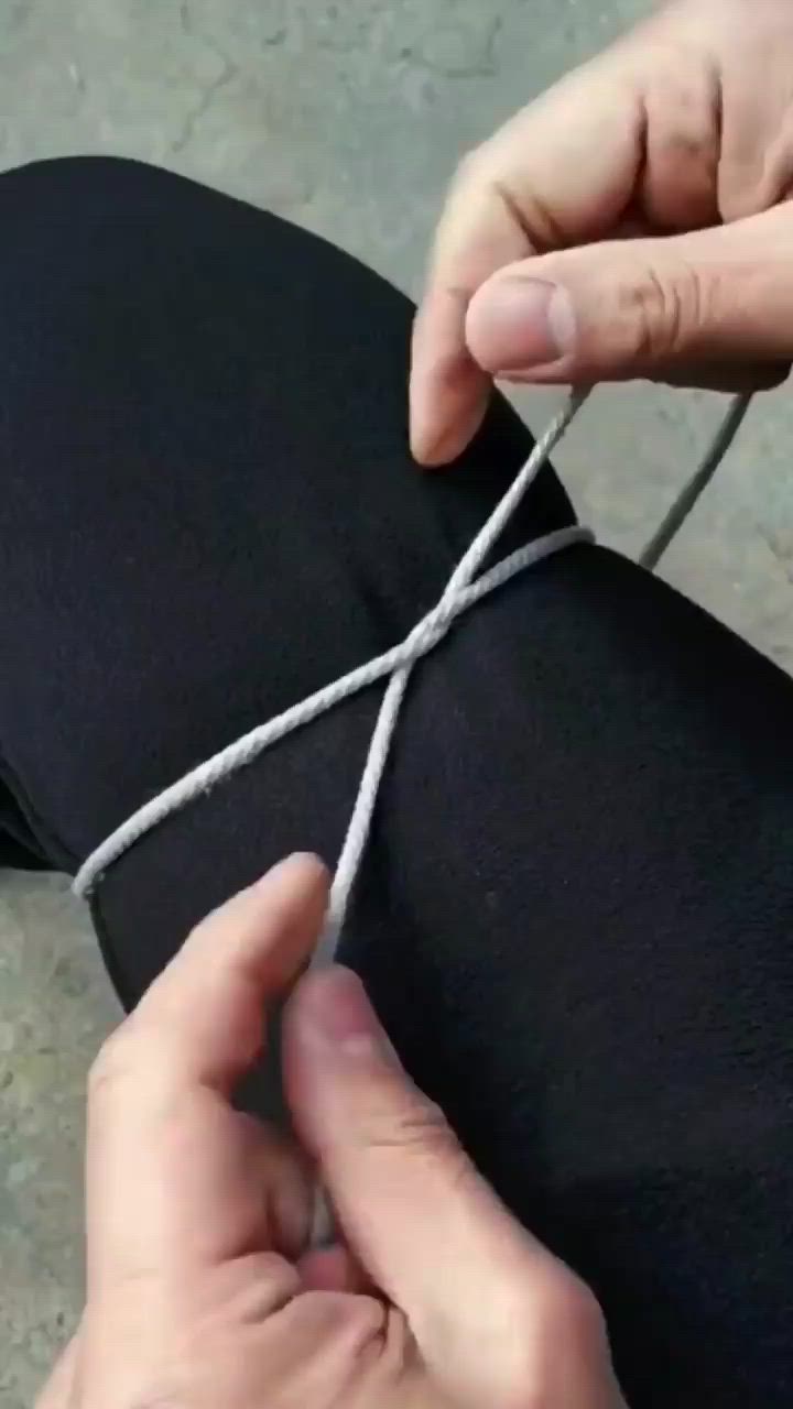 This may contain: someone is tying the end of a pair of black pants with white yarn on them