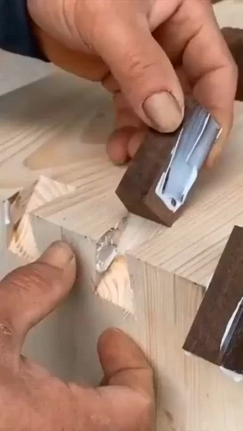 This may contain: two hands are working on some wood with metal pieces in the foreground and one hand is holding a piece of wood