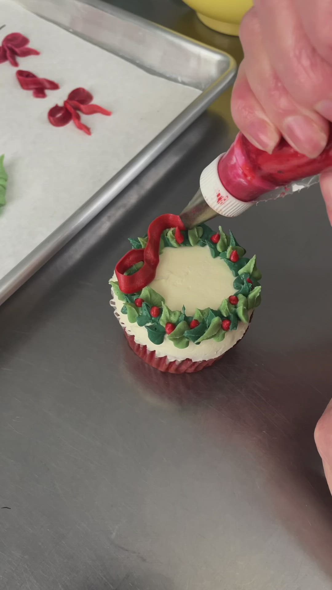 This may contain: a person is decorating a cupcake with icing