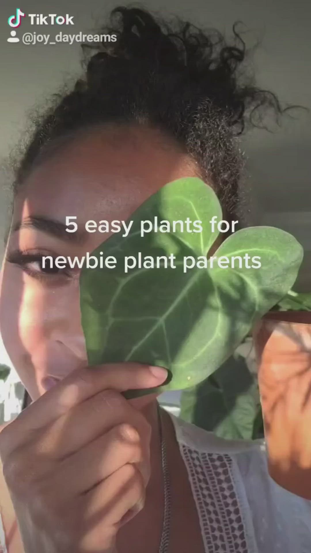 This may contain: a woman holding up a plant with the words 5 easy plants for newbie plant parents care instructions