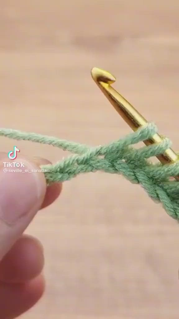 This may contain: someone is crocheting the end of a piece of green yarn with gold hardware