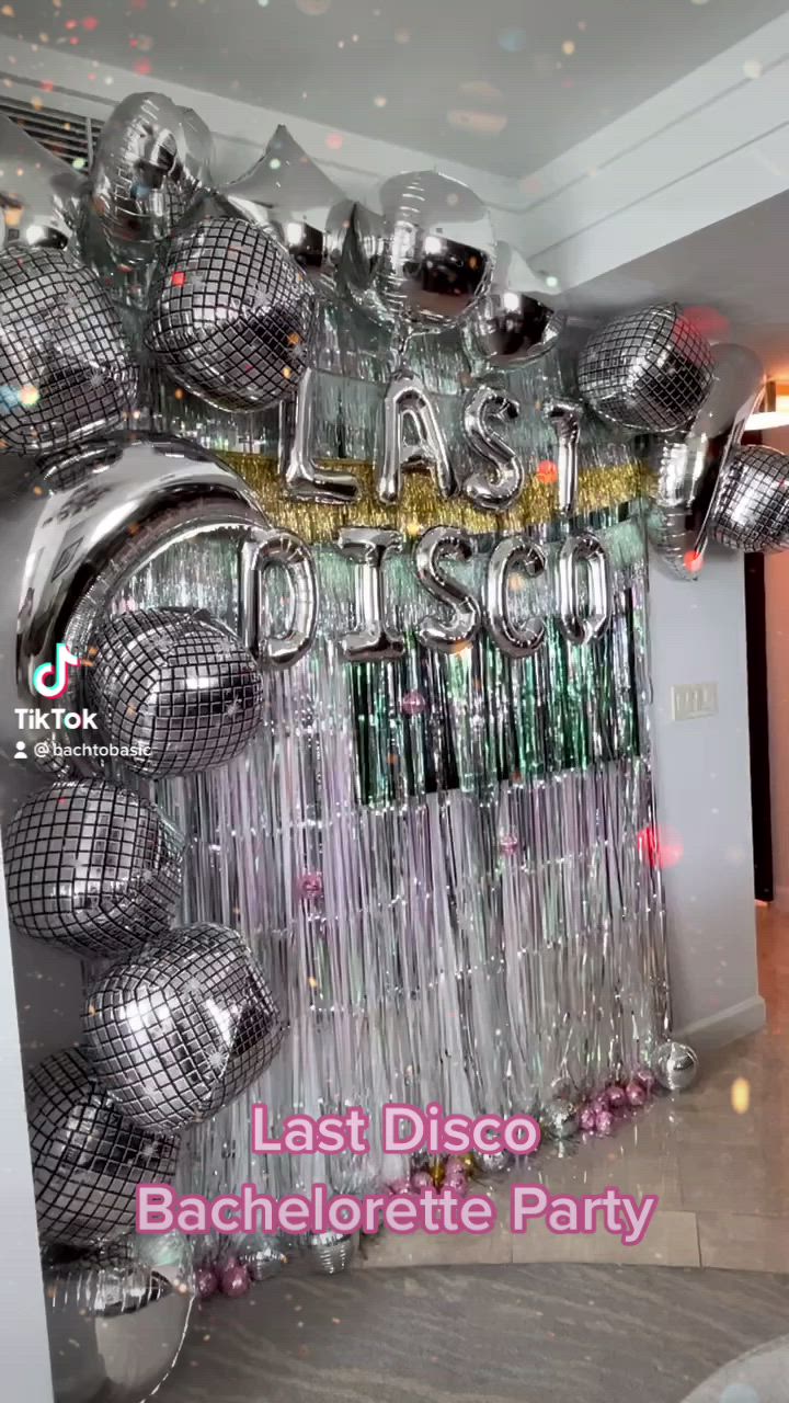 This may contain: a party decoration with silver balloons and disco balls on the wall, in front of an entrance