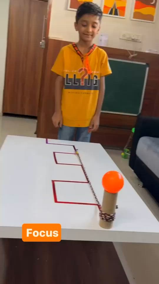 This may contain: a young boy standing in front of a table with a piece of paper on it