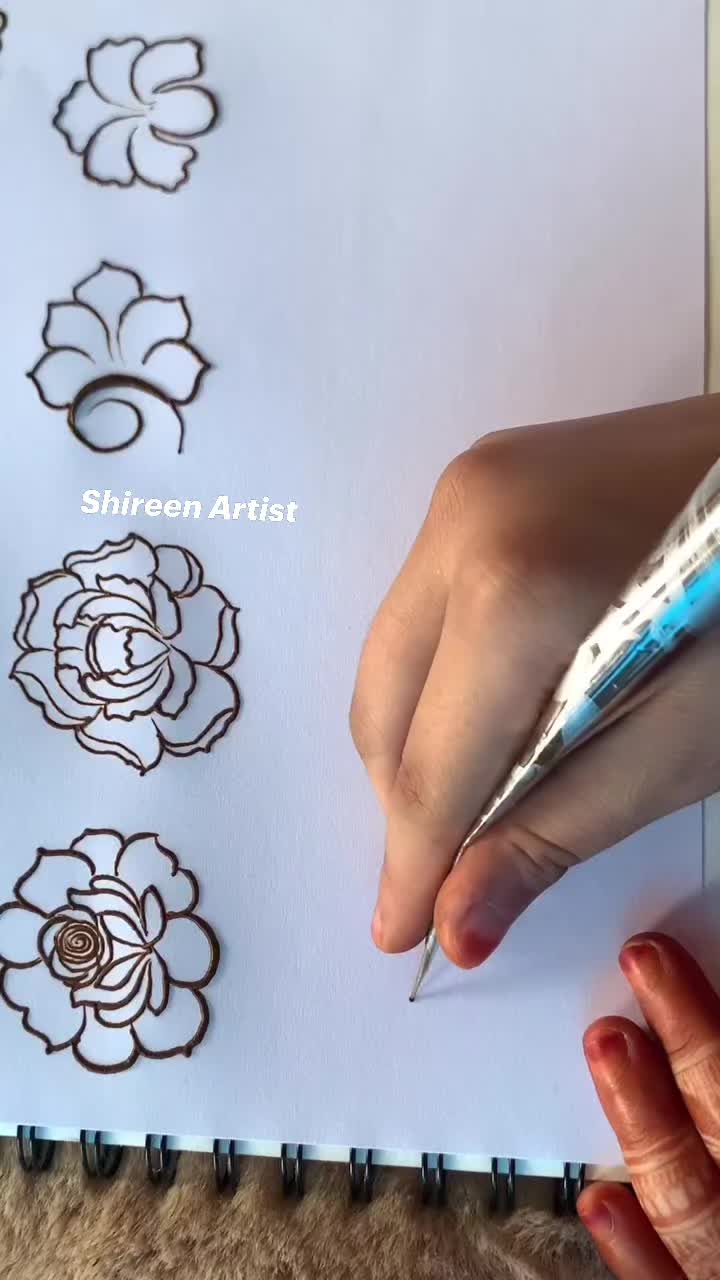 This may contain: someone is drawing flowers on paper with a pen