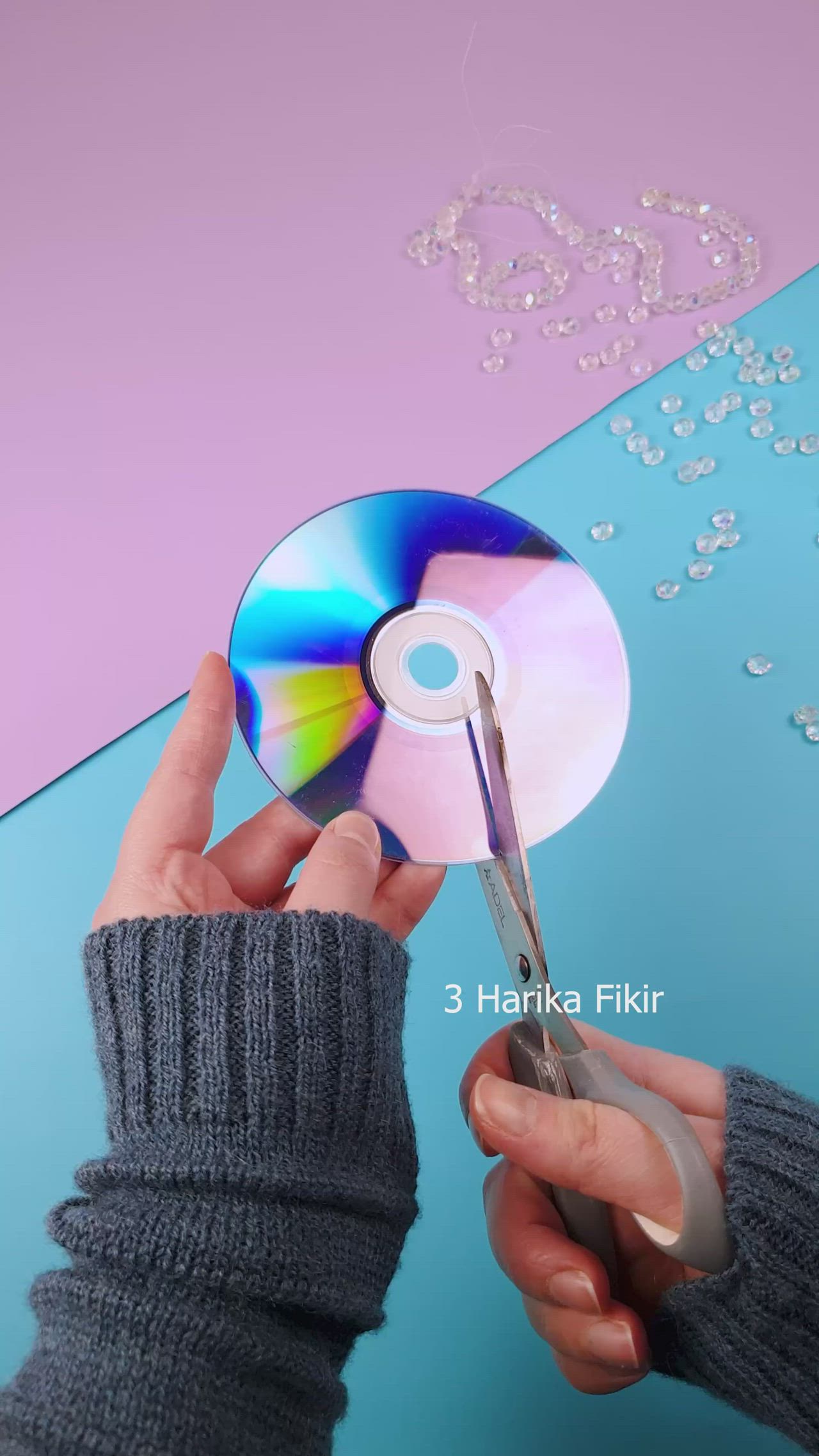 This may contain: a hand holding an ornament in front of a blue and purple background with beads