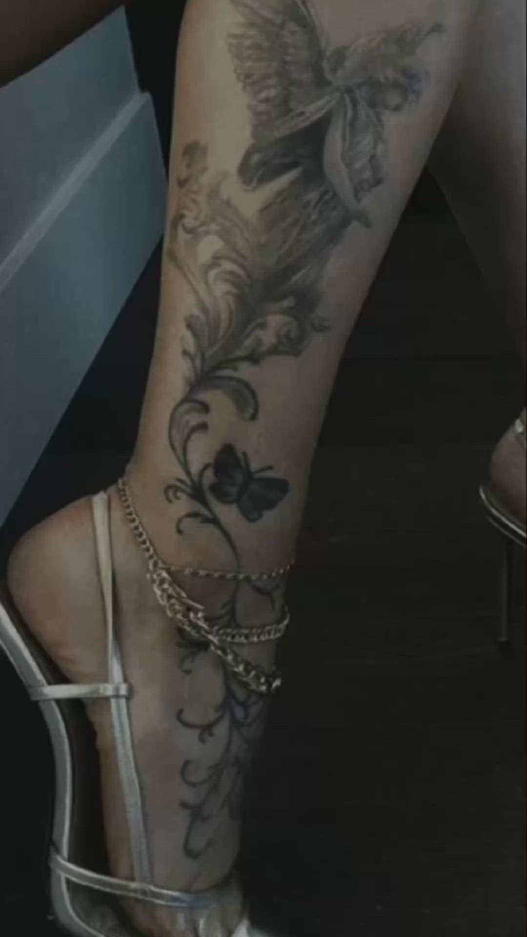 This may contain: a woman's legs with tattoos and high heels