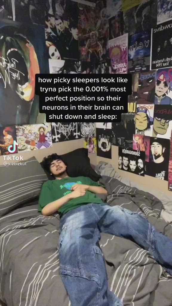 This may contain: a man laying on top of a bed next to a wall covered in pictures and posters