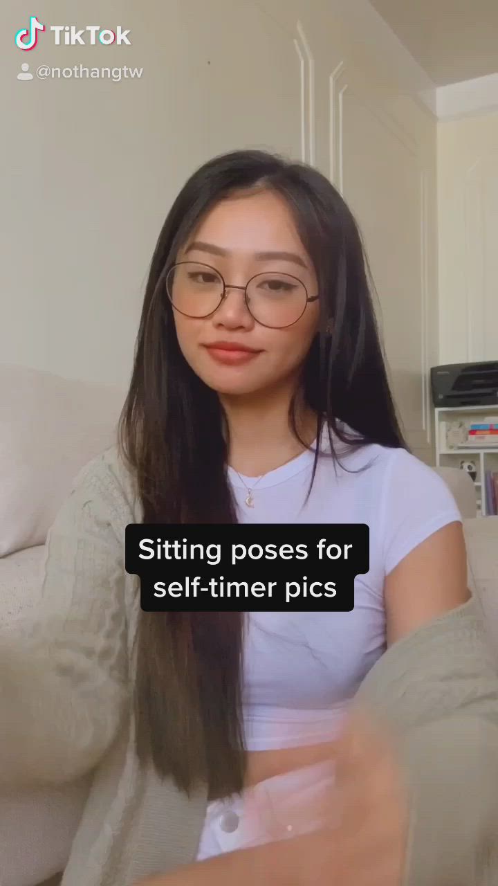 This may contain: a woman wearing glasses sitting on a couch with her hands behind her head and the caption saying sitting poses for self - timer pics