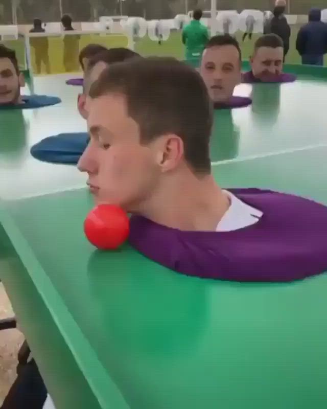 This may contain: a group of men sitting at a table with balls in their mouths and one man wearing a purple shirt