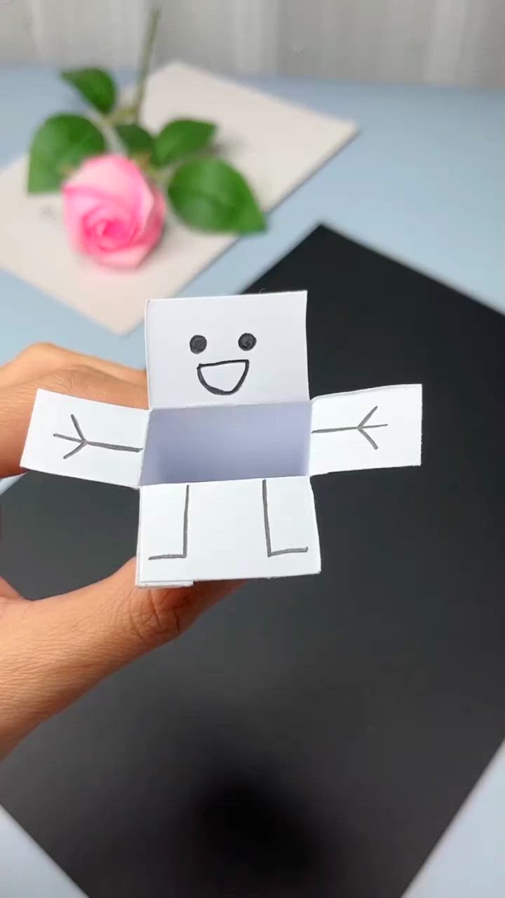 This may contain: someone holding up a piece of paper cut out to look like a person's face