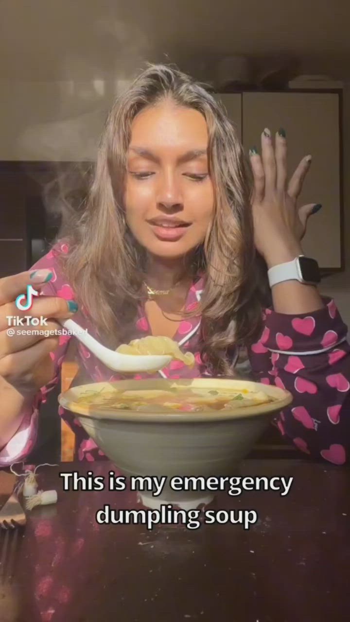 This may contain: a woman holding a spoon in front of a bowl of food with the caption, this is my emergency dumping soup