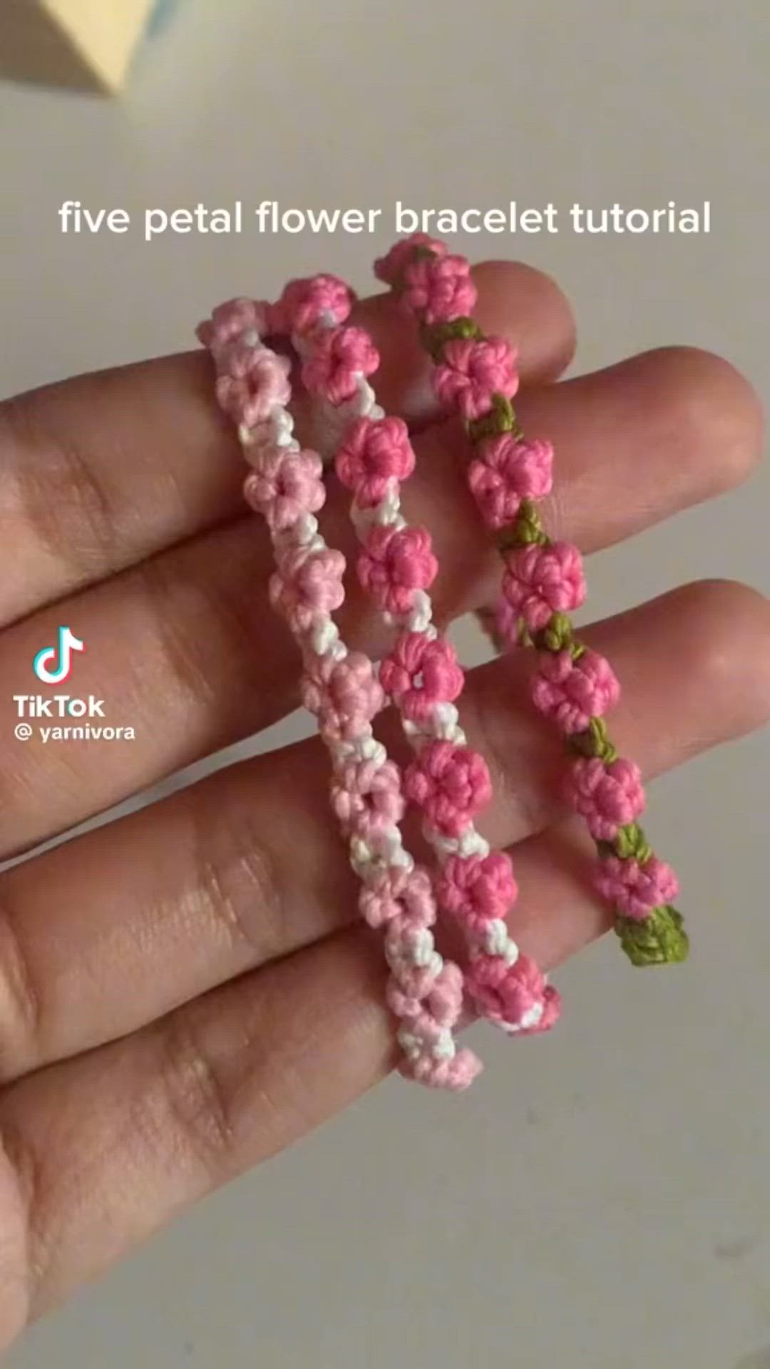 This may contain: two pink and green flower bracelets are shown in the palm of someone's hand