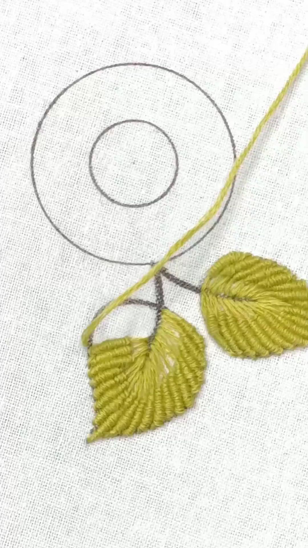 This may contain: someone is stitching leaves on a piece of fabric