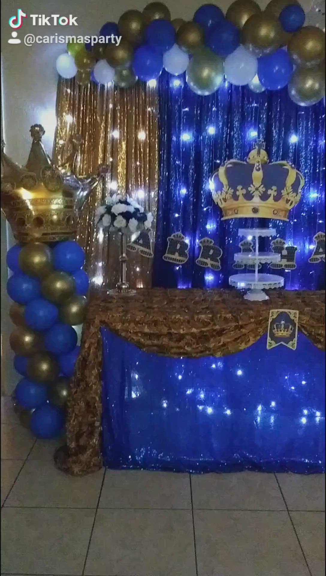 This may contain: a blue and gold birthday party setup with balloons, streamers, table cloths and decorations