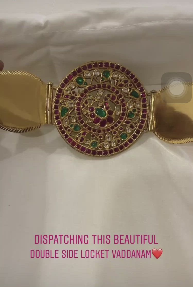 This may contain: a gold bracelet with red, green and white stones in the center on a white background