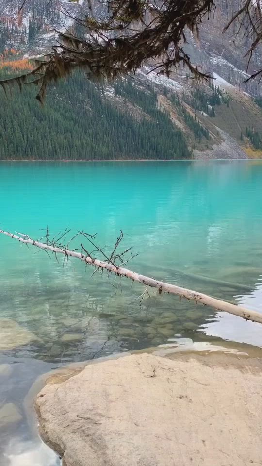 This may contain: a lake surrounded by mountains and trees with blue water