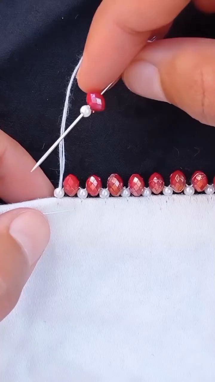 This may contain: someone is stitching beads on a piece of fabric