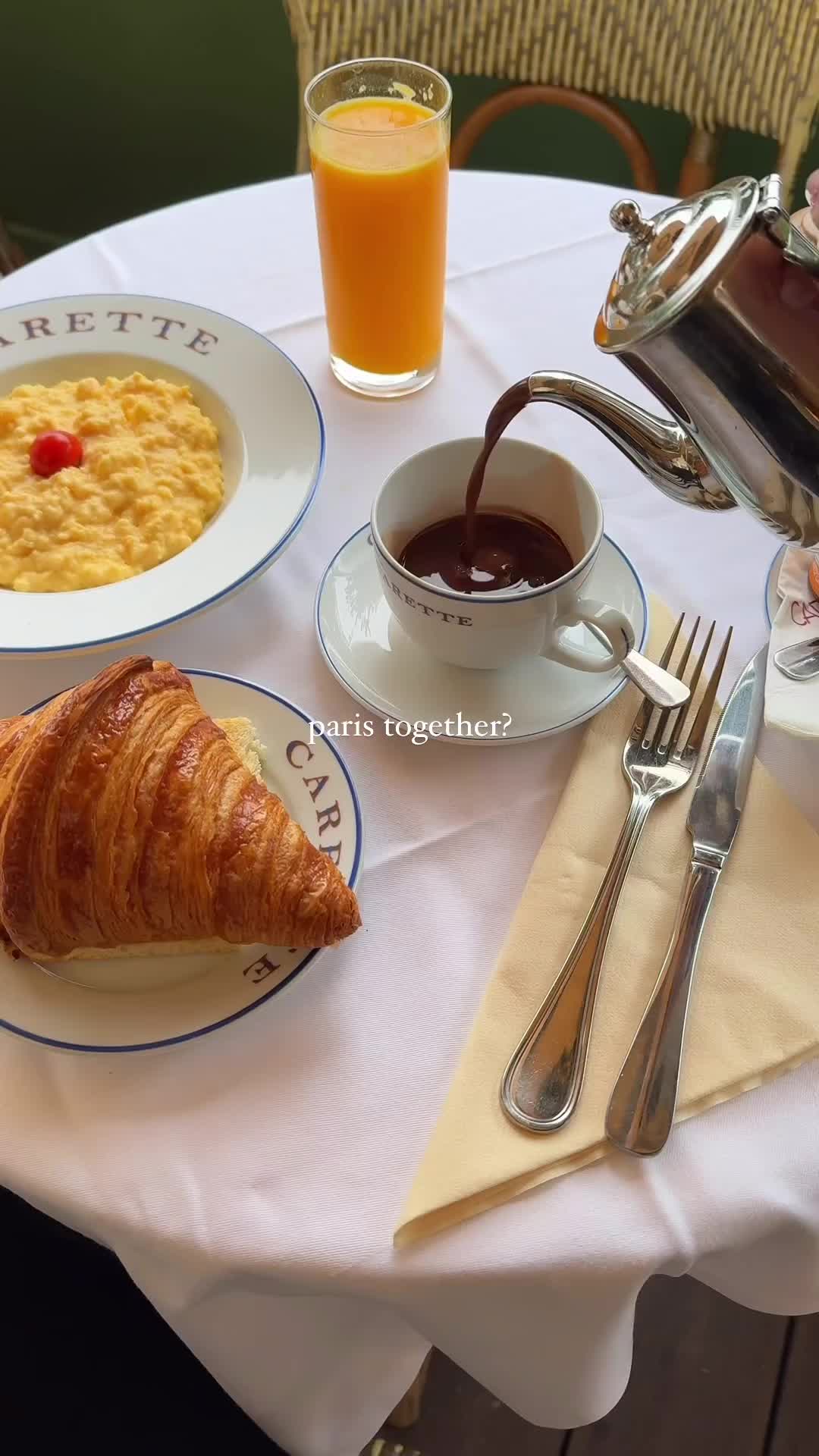 This may contain: there is a croissant, coffee and orange juice on the table with silverware