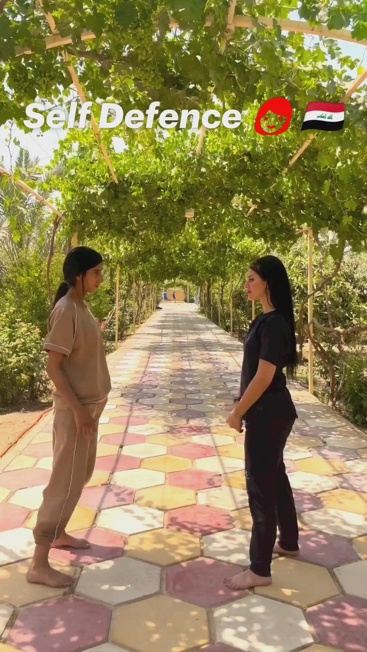 This may contain: two women standing in the middle of a walkway with trees on both sides and words self defence above them