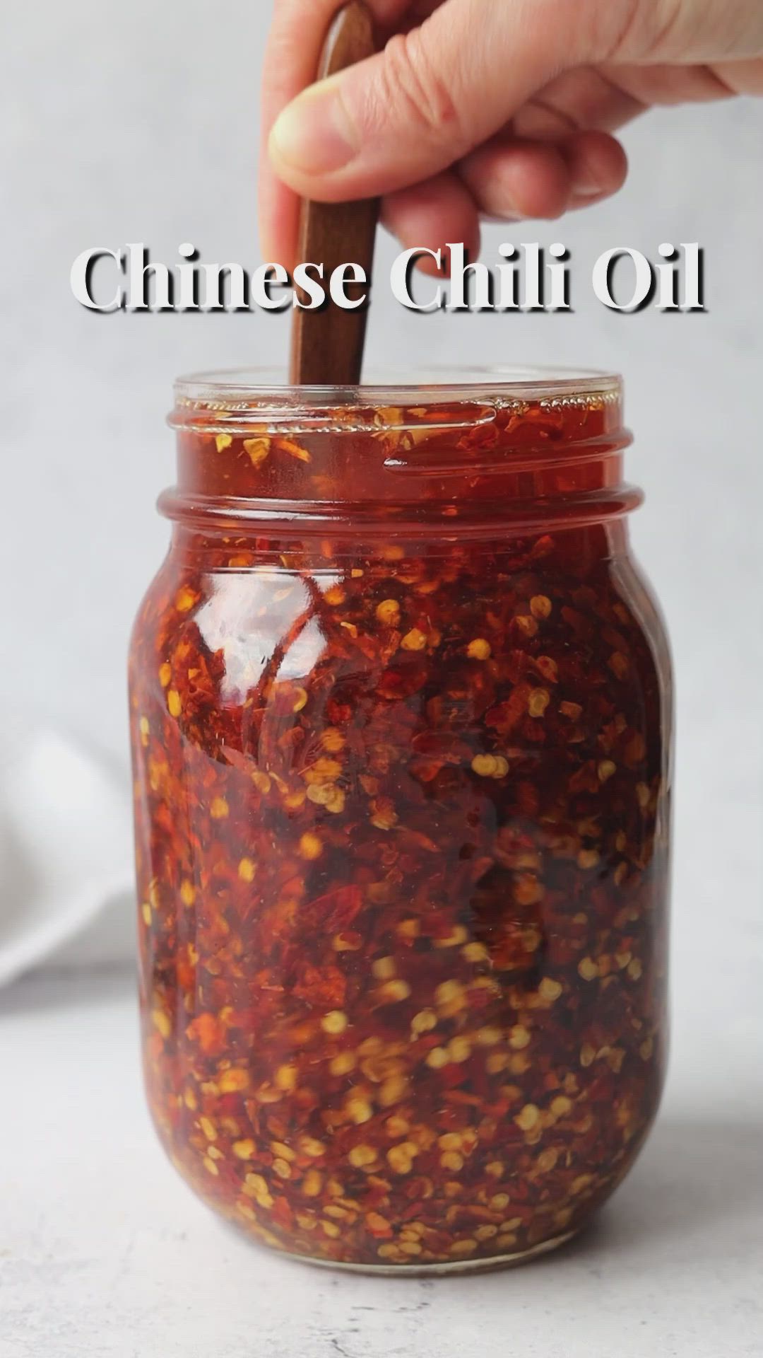 This may contain: a jar filled with chili condiment sitting on top of a table next to a spoon