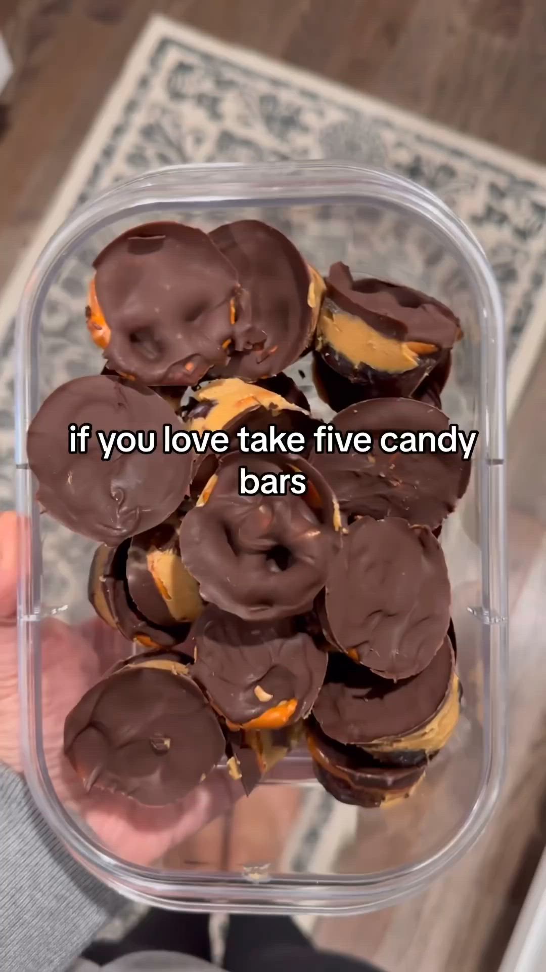 This may contain: a person holding up a plastic container filled with chocolate covered donuts that say if you love take five candy bars