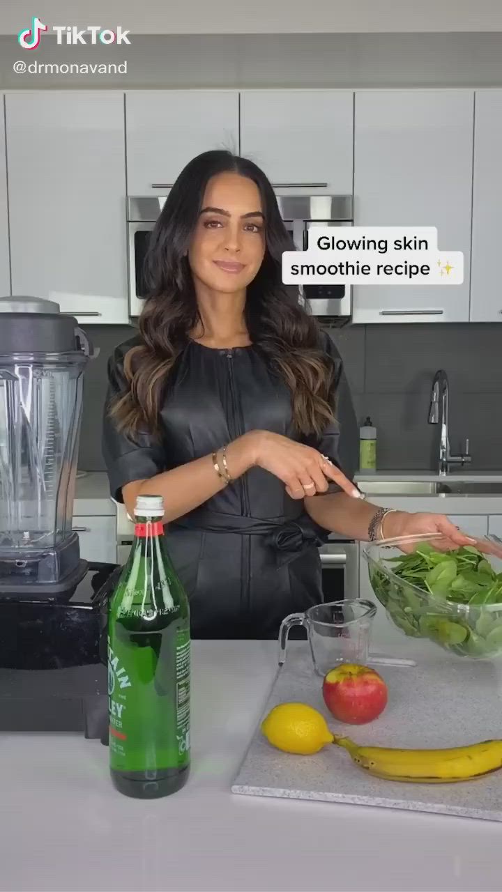 This may contain: a woman standing in front of a counter cutting vegetables with a blender behind her