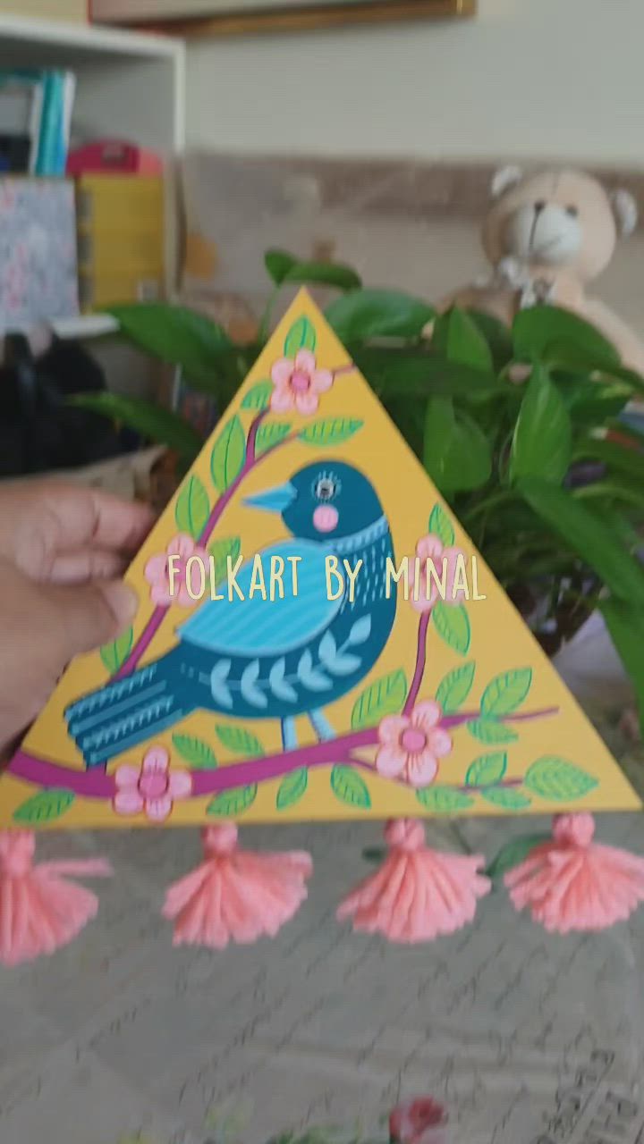 This may contain: a hand holding a triangle shaped card with a blue bird on it