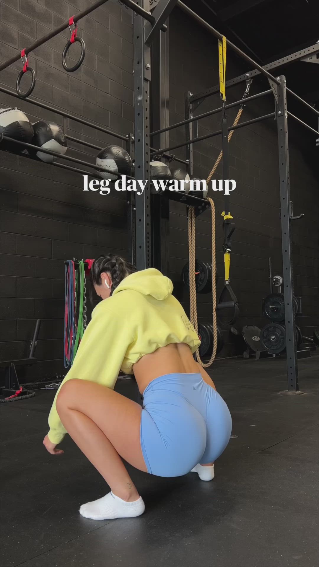 This may contain: a woman squatting down in front of a gym equipment rack with the words leg day warm up on it